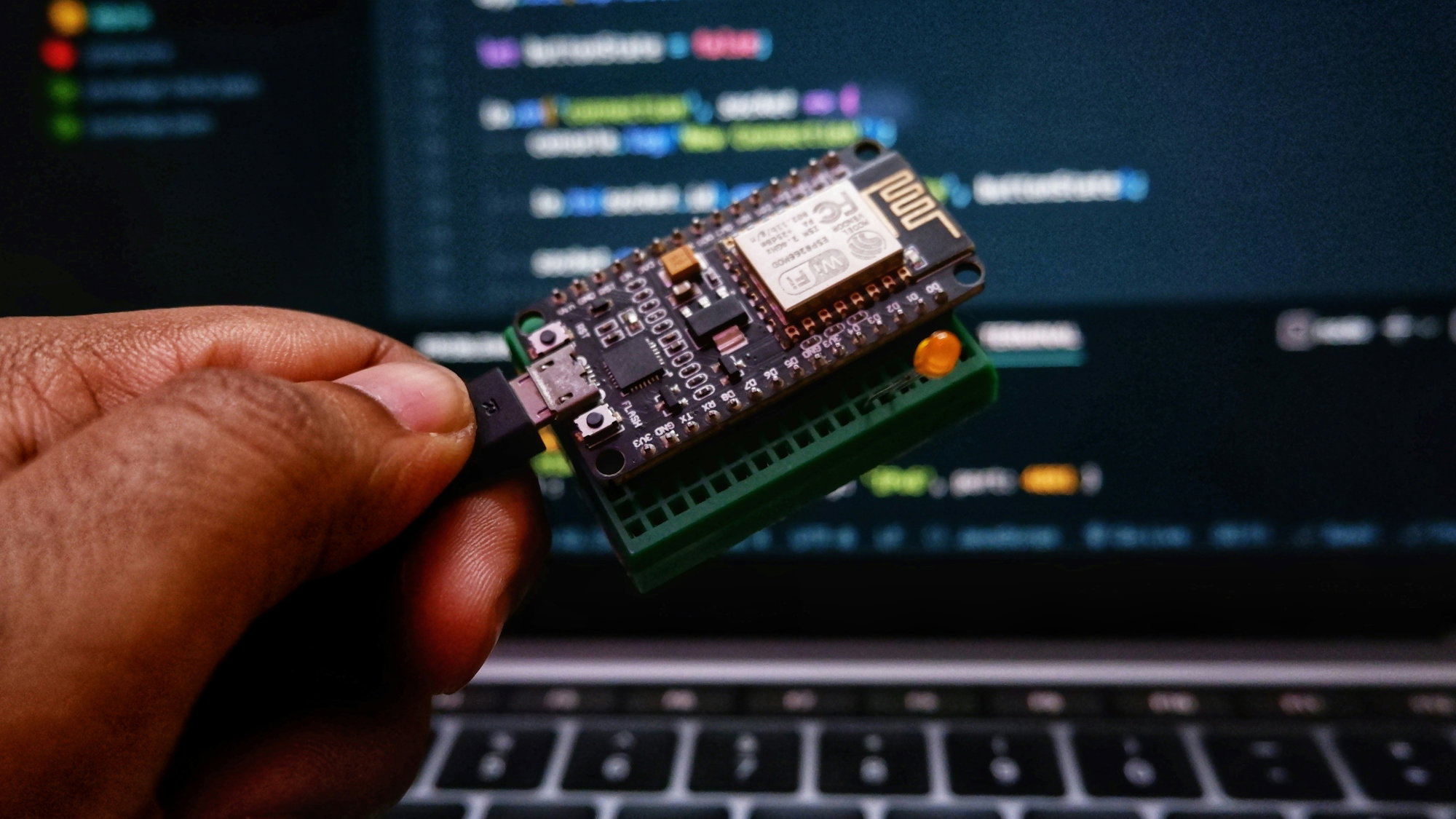 a-person-holding-a-small-device-in-front-of-a-laptop.jpg a person holding a small device in front of a laptop